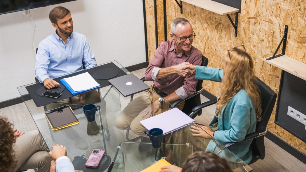 From above of business partners shaking hands during conference meeting